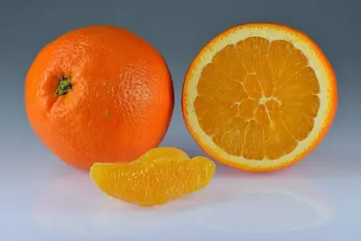 An orange beside one cut in half, and segments